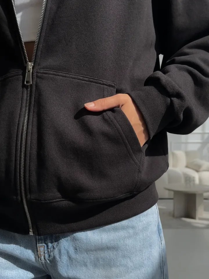 Close-up of the zipper and pocket on the black NAZZANI hoodie